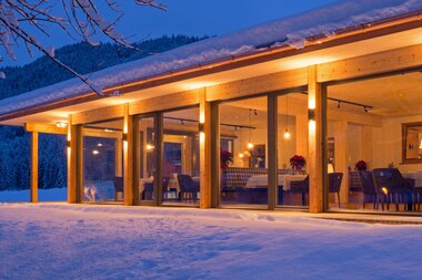 Modern building with large windows, snow-covered ground, and winter landscape in the background.