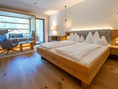Modernes Schlafzimmer mit zwei Betten, Holzinterieur und Fensterblick auf die Natur.