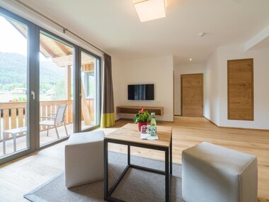Moderne Wohnküche mit zwei Stühlen, einem Tisch und Fernseher, Blick auf Berge.