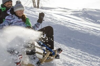A couple is sledding down a snowy hill, enjoying the ride together.